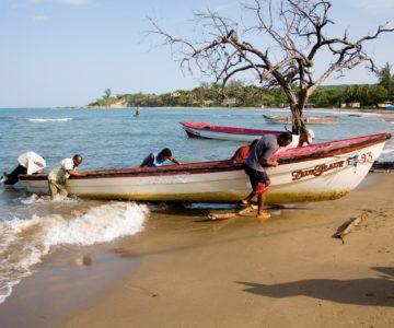 Fischer mit Boot am Strand an Jamaicas Südküste