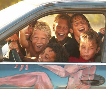 Lachende Kinder in bunt bemaltem Auto auf Curacao