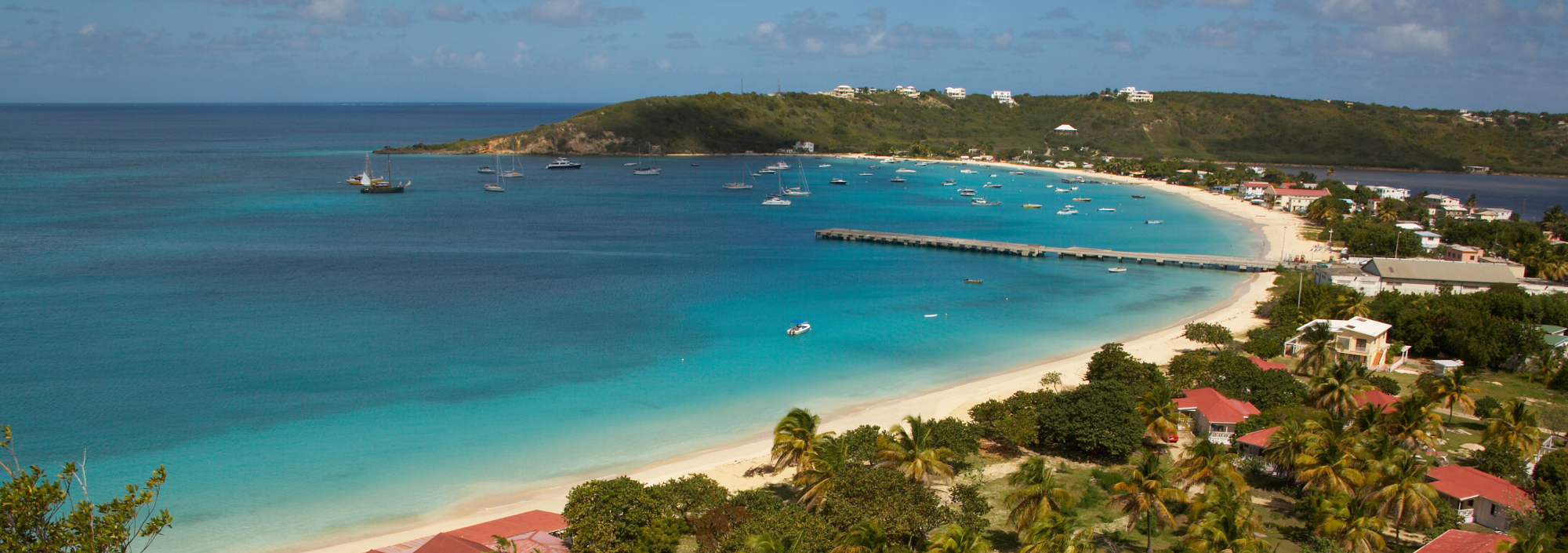 Bucht von Anguilla mit kleinem Ort, Palmen, weißem Sandstrand und ankernden Jachten