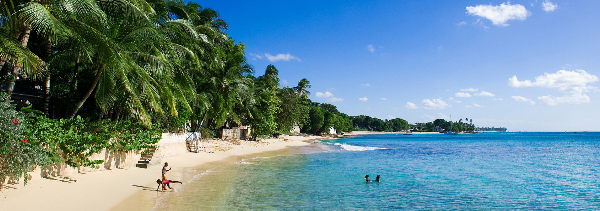 Schmale Strandbucht auf Barbados mit Palmen und badenden Kindern