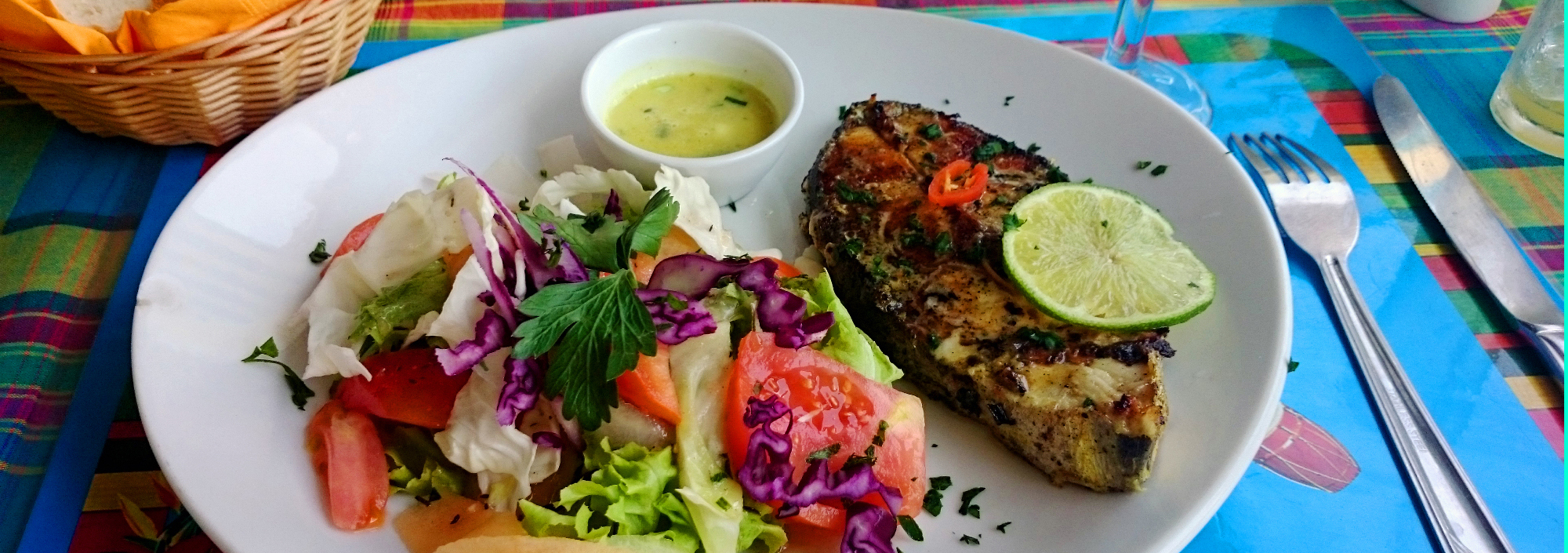 Teller mit buntem karibischem Gericht mit Salat und Fisch