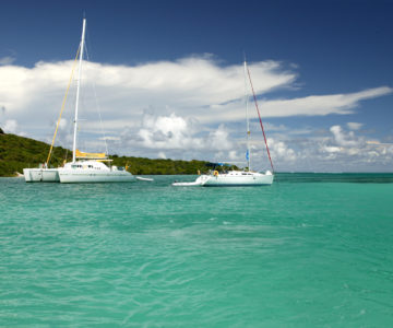 Ein Katamaran und ein klassisches Segelboot vor Anker in den Grenadinen