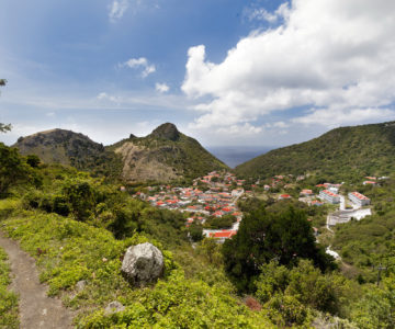 Blick über Saba mit Ort mit weißen Häusern mit roten Dächern und umliegenden Bergen mit Wanderpfad