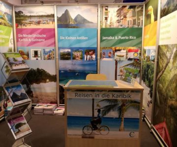 Messestand der CI Caribicinseln GmbH mit farbigen Bannern