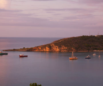 Blick über eine Bucht auf Anguilla mit Fischerbooten bei Sonnenuntergang